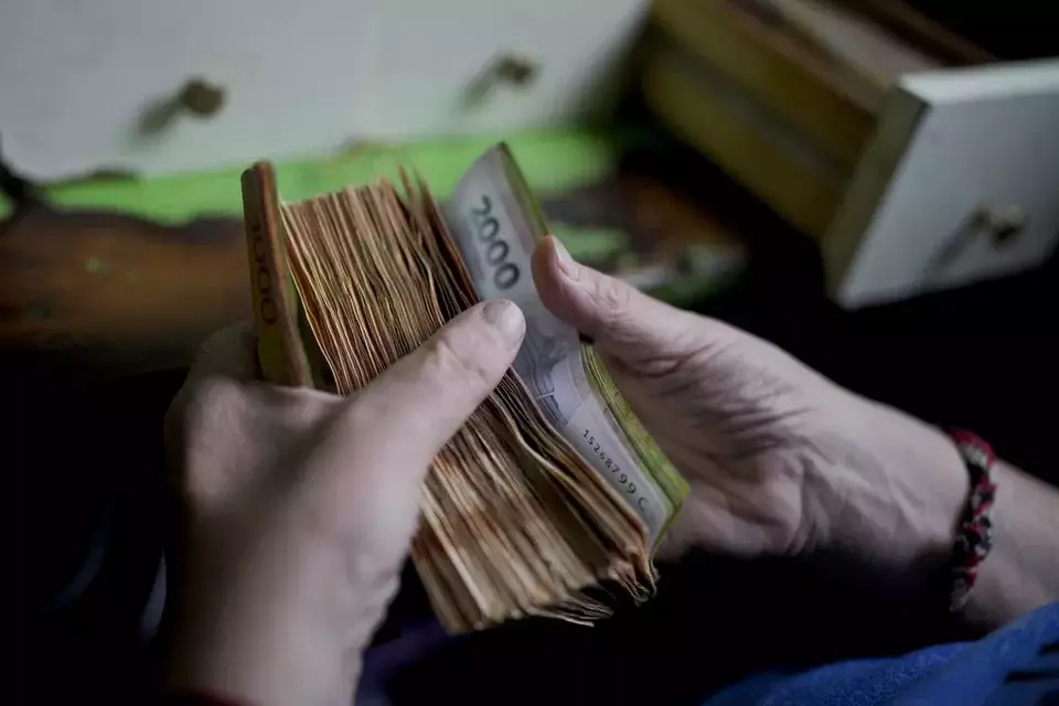 File - A worker counts money at a grocery store in Buenos Aires, Argentina, Nov. 21, 2023. Prices have surged so dramatically that the government has multiplied the size of its biggest banknote in circulation to 10,000 peso note, five times the value of the previous biggest bill, according to the central bank on May 8, 2024, and the new bill is expected circulate in June. (AP Photo/Natacha Pisarenko, File)