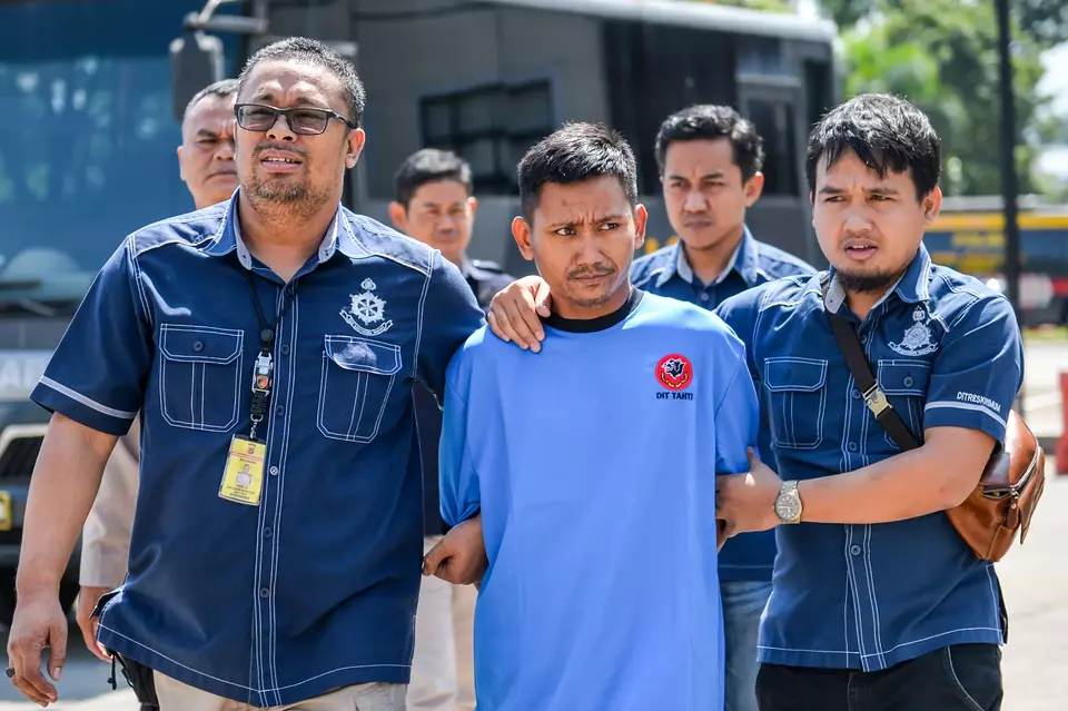 Police officers in plain clothes escort Pegi Setiawan, center, the suspected mastermind in the 2016 murder of a Cirebon couple, at the West Java Police headquarters in Bandung, Sunday, May 26, 2024. (Antara Photo/Raisan Al Farisi)
