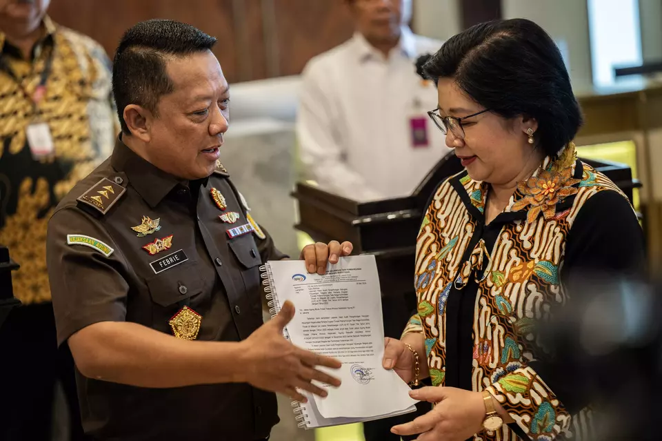 Febrie Adriansyah, left, the deputy attorney general for special crimes, receives documents detailing alleged state losses from a major graft scandal at the state-owned tin miner Timah from Agustina Arumsari, an official with the State Development Finance Controller (BPKP) at the Attorney General's Office in Jakarta, Wednesday, May 29, 2024. (Antara Photo/Bayu Pratama)