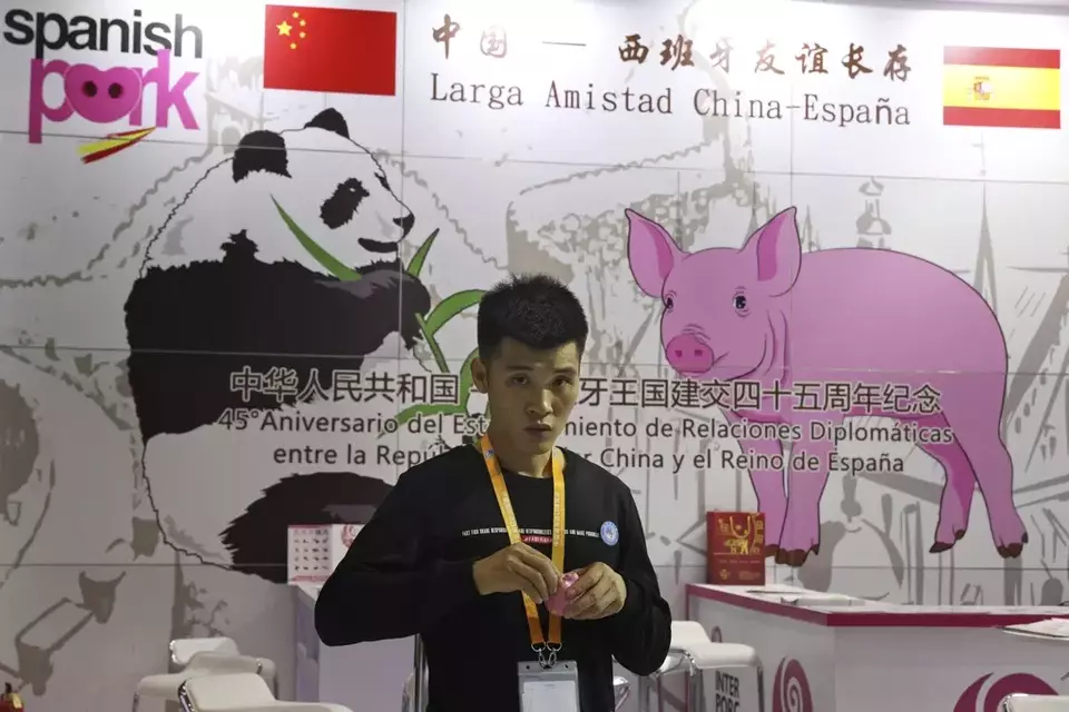 FILE - A promoter at a booth for imported Spanish pork prepares for another day at the China International Import Expo in Shanghai, on Nov. 6, 2018. (AP Photo/Ng Han Guan)