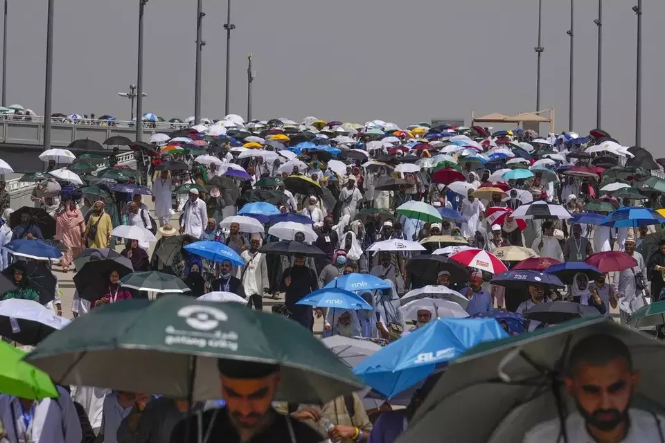 FILE - Muslim pilgrims use umbrellas to shield themselves from the sun as they arrive to cast stones at pillars in the symbolic stoning of the devil, the last rite of the annual hajj, in Mina, near the holy city of Mecca, Saudi Arabia, Tuesday, June 18, 2024. (AP Photo/Rafiq Maqbool)