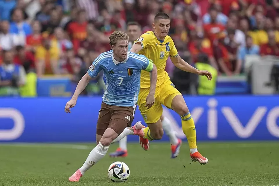 Kevin De Bruyne, left, fights for the ball with Vitaliy Mykolenko during a Group E match between Ukraine and Belgium at the Euro 2024 soccer tournament in Stuttgart, Germany, Wednesday, June 26, 2024. (AP Photo/Ariel Schalit)
