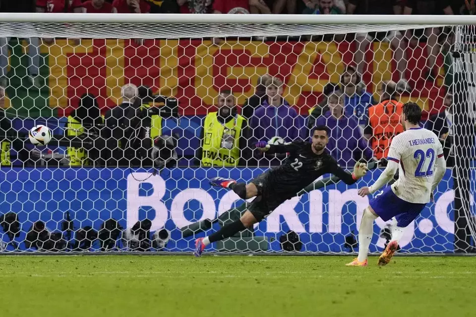 Theo Hernandez of France, right, scores the deciding goal in a shootout to win a quarter-final match between Portugal and France at the Euro 2024 soccer tournament in Hamburg, Germany, Friday, July 5, 2024. (AP Photo/Frank Augstein)