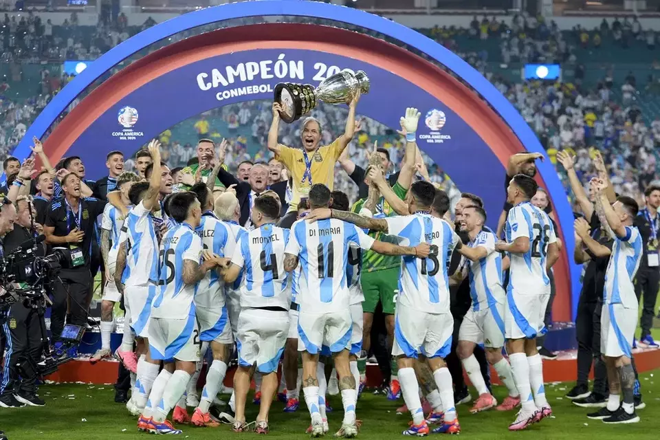 Argentina kitman Mario De Stefano holds up the trophy as he celebrates with players after defeating Colombia in the Copa America final soccer match in Miami Gardens, Florida, Monday, July 15, 2024. (AP Photo/Rebecca Blackwell)