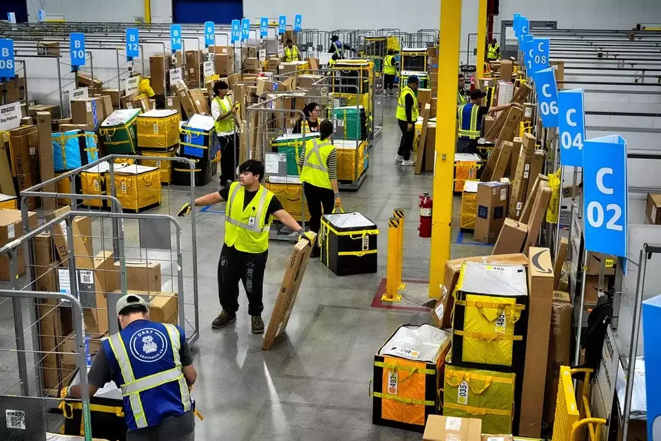 FILE - Amazon employees load packages on carts before being put on to trucks for distribution for the annual Prime Day event on Tuesday, July 16, 2024, in South Gate, Calif. (AP Photo/Richard Vogel)