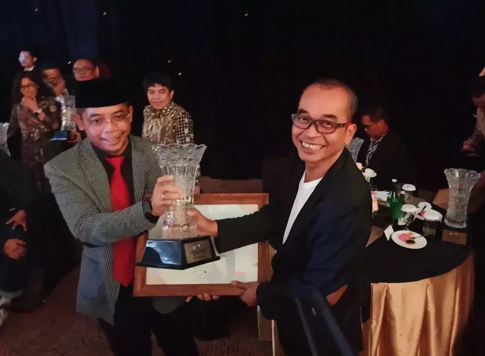 Taxation Director General Suryo Utomo, left, hands a trophy and certificate of recognition to Investor Daily Chief Editor Djaka Susila in Jakarta, Friday, July 26, 2024. (Investor Daily/Arnoldus Kristianus)