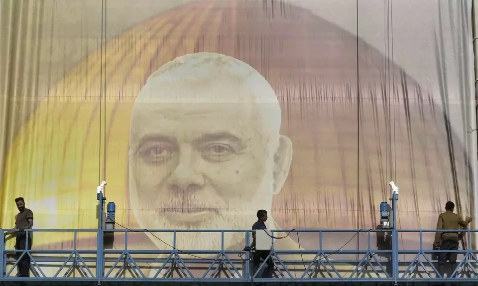 Iranian workers install a huge banner on a wall showing a portrait of Hamas leader Ismail Haniyeh and the Dome of Rock Mosque at the Al-Aqsa Mosque compound of Jerusalem at Felestin (Palestine) Sq. in Tehran, Iran, Wednesday, July 31, 2024. Haniyeh was assassinated in Tehran, Iran