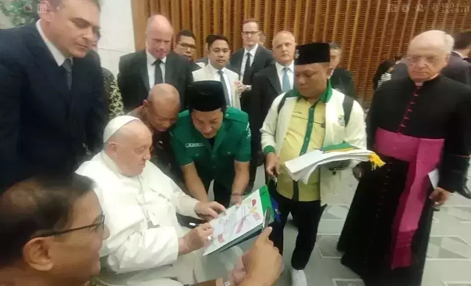 This grab from a video provided by GP Ansor shows Pope Francis signing a declaration on religious tolerance presented by Indonesian young faith leaders at The Vatican, Wednesday, Aug. 22, 2024.