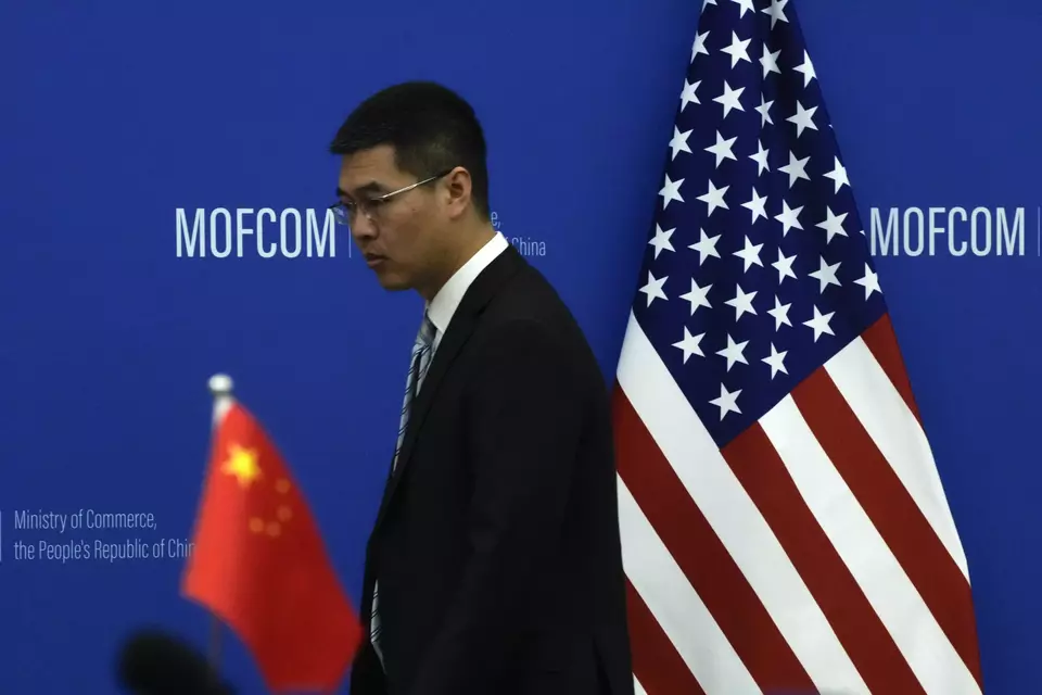 FILE - A Chinese official walks by the China and US national flags before a meeting between Commerce Secretary Gina Raimondo and Chinese Minister of Commerce Wang Wentao at the Ministry of Commerce in Beijing on Aug. 28, 2023. (AP Photo/Andy Wong, Pool, File)