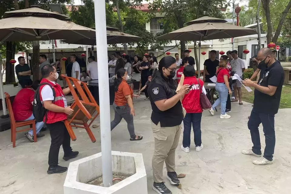 In this photo provided by the Bureau of Immigration, Philippine authorities, wearing a red bib or black shirt, monitor activities during a raid on a suspected illegal online gaming and cyberscam complex in Lapu-Lapu city, Cebu province, central Philippines Saturday, Aug. 31, 2024. (Bureau of Immigration via AP)