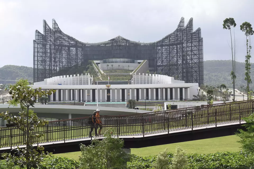 Construction workers walk along a pedestrian bridge in front of the half-completed State Palace in the future national capital, Nusantara, in North Penajam Paser Regency, East Kalimantan, Saturday, Aug. 31, 2024. (Antara Photo/M Risyal Hidayat)