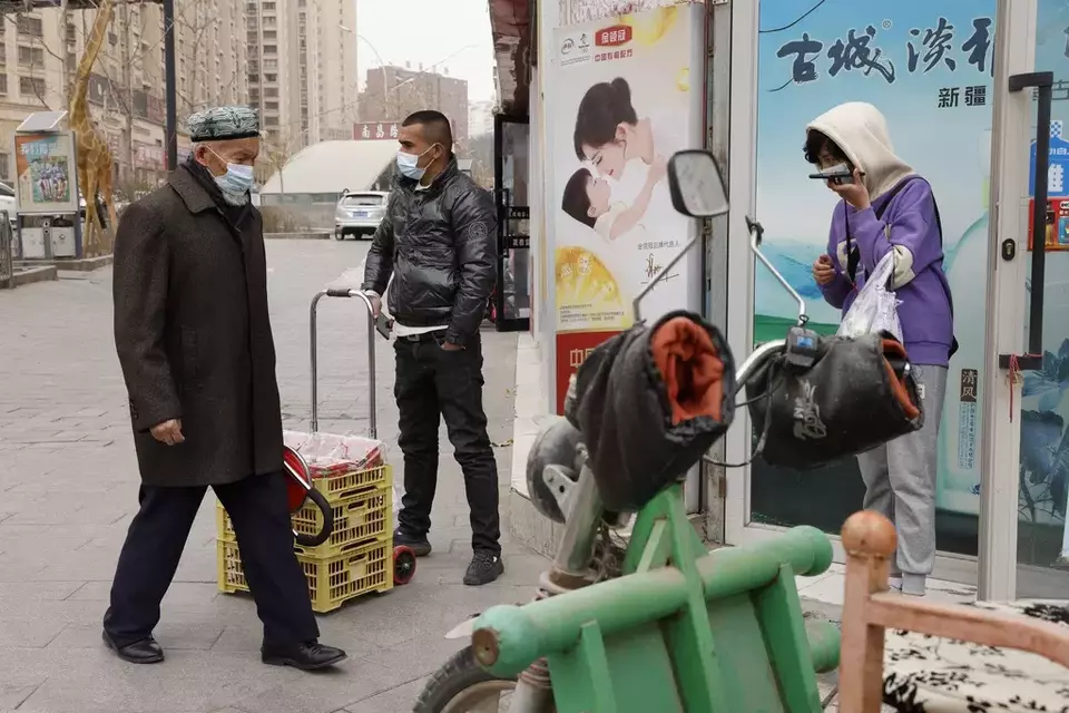 In this March 18, 2021, file photo, residents wearing masks walk along the streets of Aksu in western China's Xinjiang region. (AP Photo/Ng Han Guan)