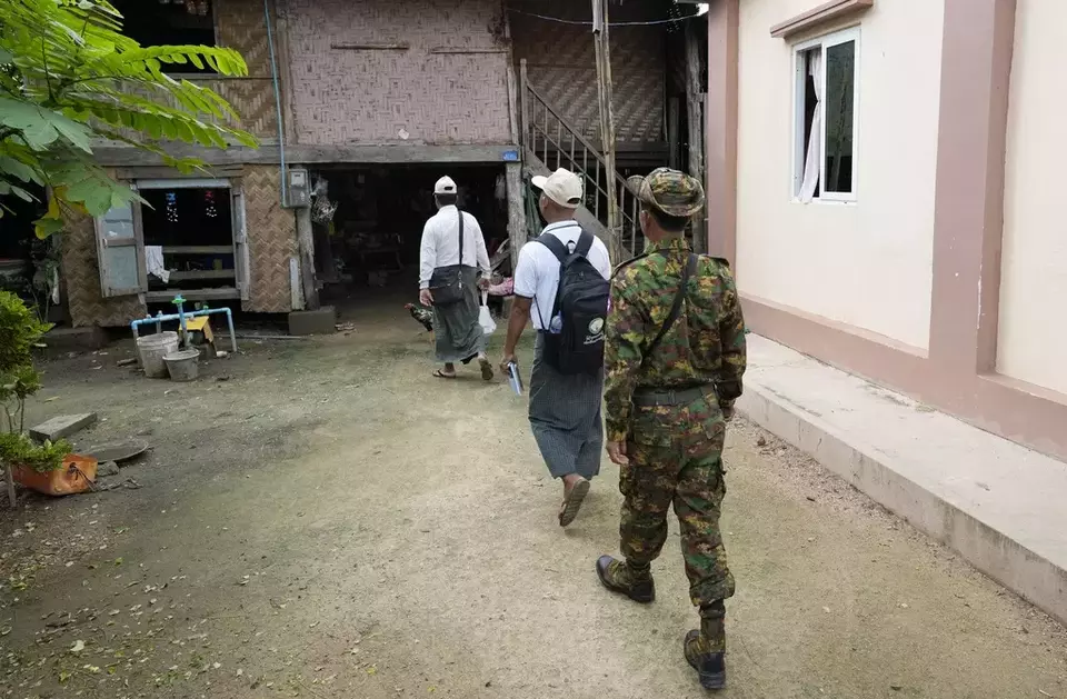 A soldier provides security to census enumerators who collect information in Naypyitaw, Myanmar Tuesday, Oct. 1, 2024 as the country holds a national census to compile voter lists for a general election and to analyze population and socioeconomic trends. (AP Photo/Aung Shine Oo)