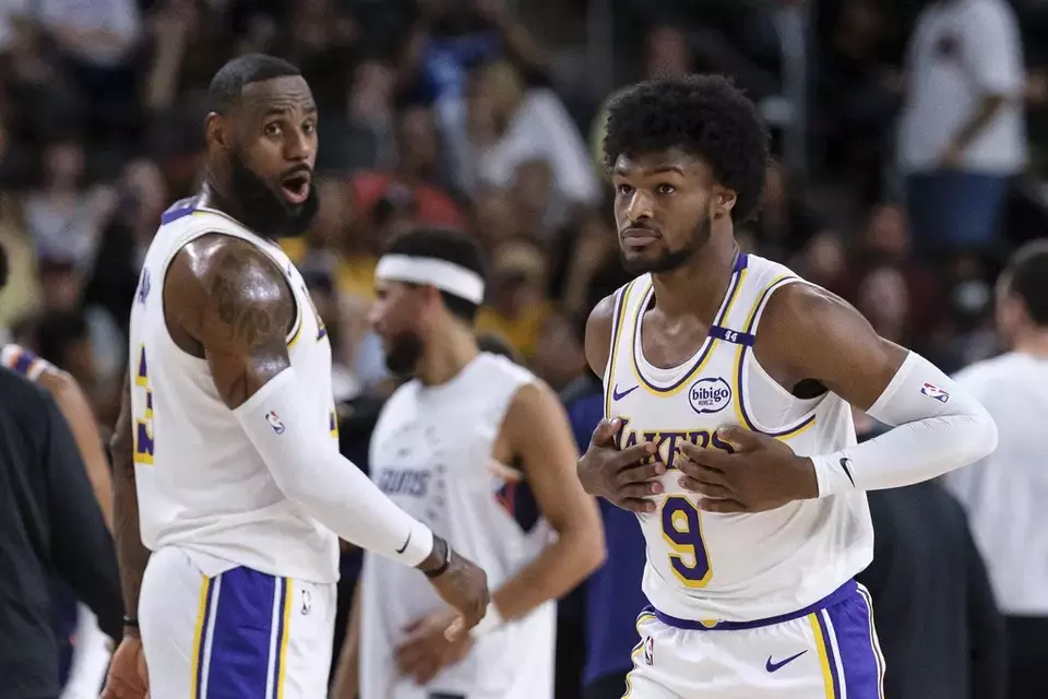 Los Angeles Lakers guard Bronny James (9), right, steps onto the court with Los Angeles Lakers forward LeBron James (23) during the first half of a preseason NBA basketball game Sunday, Oct. 6, 2024, in Palm Desert, Calif. (AP Photo/William Liang)

