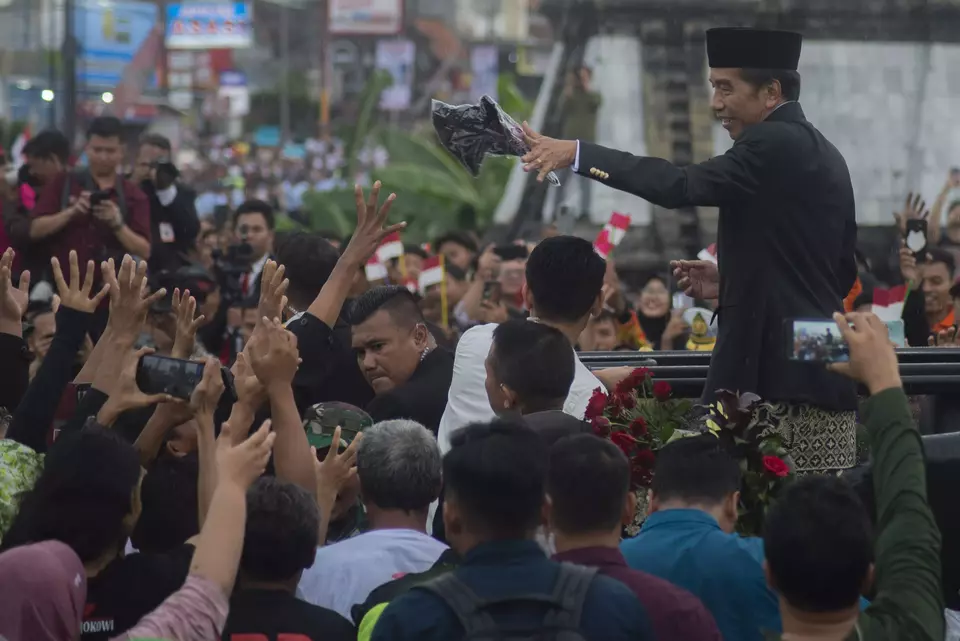 Joko Widodo distributes t-shirts to supporters as his motorcade passes Colomadu Street in Karanganyar, Central Java, Sunday, Oct. 20, 2024. (Antara Photo/Aloysius Jarot Nugroho)