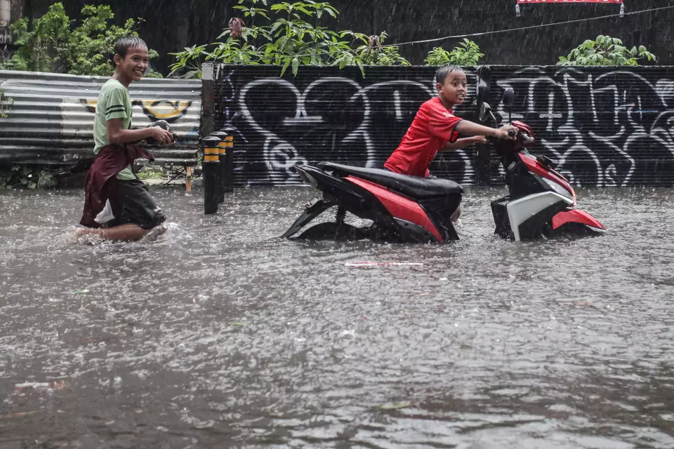 Two children push a motorcycle through floodwaters on Jalan Cipete Utara, Jakarta, on Tuesday, Nov. 5, 2024. The flooding was caused by heavy rain in Jakarta and surrounding areas, compounded by poor drainage systems. (ANTARA FOTO/Zaky Fahreziansyah).