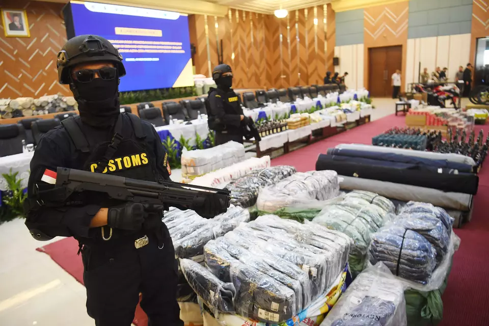 Customs agents guard smuggled goods shown at a press conference in Jakarta on Nov. 14, 2024. (Antara Photo/Akbar Nugroho Gumay)