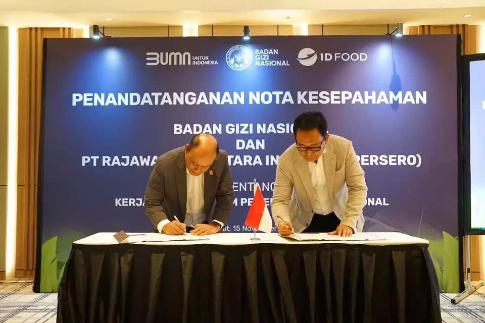 National Nutrition Agency Head Dadan Hindayana, left, and ID Food CEO Sis Apik Wijayanto sign a memorandum of understanding on collaborative works to implement the free nutritious food program for school-aged children in Jakarta, Friday, Nov. 15, 2024. (Handout)