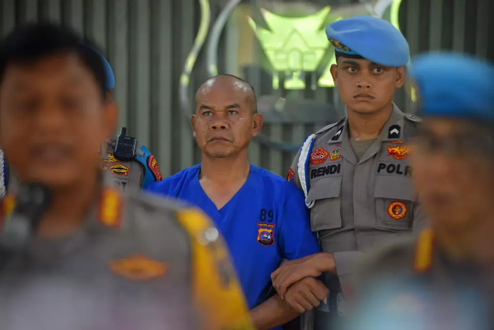 Adjunct Commissioner Dadang Iskandar, center, is escorted by police at the West Sumatra Police headquarters in Padang, Saturday, Nov. 23, 2024. He is accused of murdering fellow officer Ryanto Ulil Anshar at the South Solok District Police where they worked. (Antara Photo/Iggoy el Fitra)