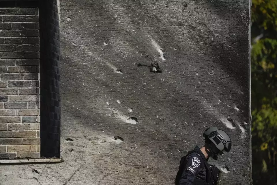 A police bomb squad officer inspects the site where a rocket fired from Lebanon landed in a backyard in Kiryat Shmona, northern Israel, Tuesday Nov. 26, 2024. (AP Photo/Leo Correa)