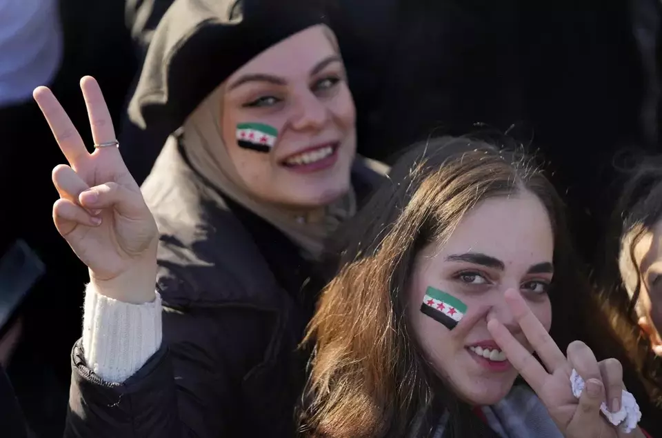 Syrian women flash victory signs with the colour of "revolutionary" Syrian flag on their faces, during a celebratory demonstration following the first Friday prayers since Bashar Assad