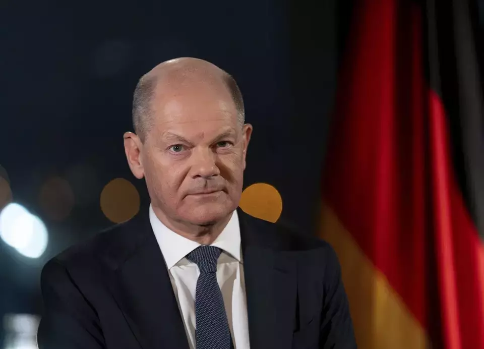 German Chancellor Olaf Scholz sits in front of the backdrop of the Reichstag illuminated by spotlights during a photo session after the recording of his New Year s address in the Chancellery in Berlin, Germany, Dec. 29, 2024. (Soeren Stache/dpa via AP)
