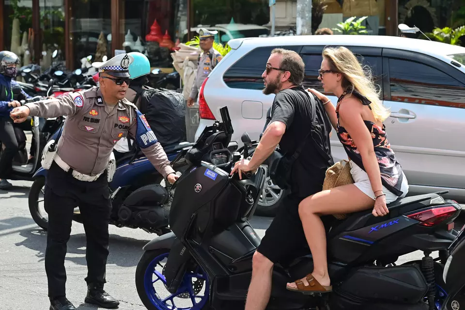 A traffic policeman stops a couple of foreign tourists for a traffic offense in the Kerobokan area, Badung Regency, Bali, Monday, Jan. 6, 2025. (Antara Photo/Fikri Yusuf)