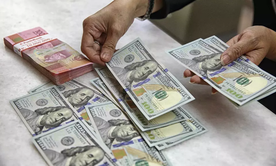 A cashier counts US dollars and Indonesian rupiah at a currency exchange in Jakarta, Friday, Feb. 7, 2025. The rupiah strengthened to close at Rp16,282 per US dollar at the end of the week. (Beritasatu Photo/Joanito De Saojoao)