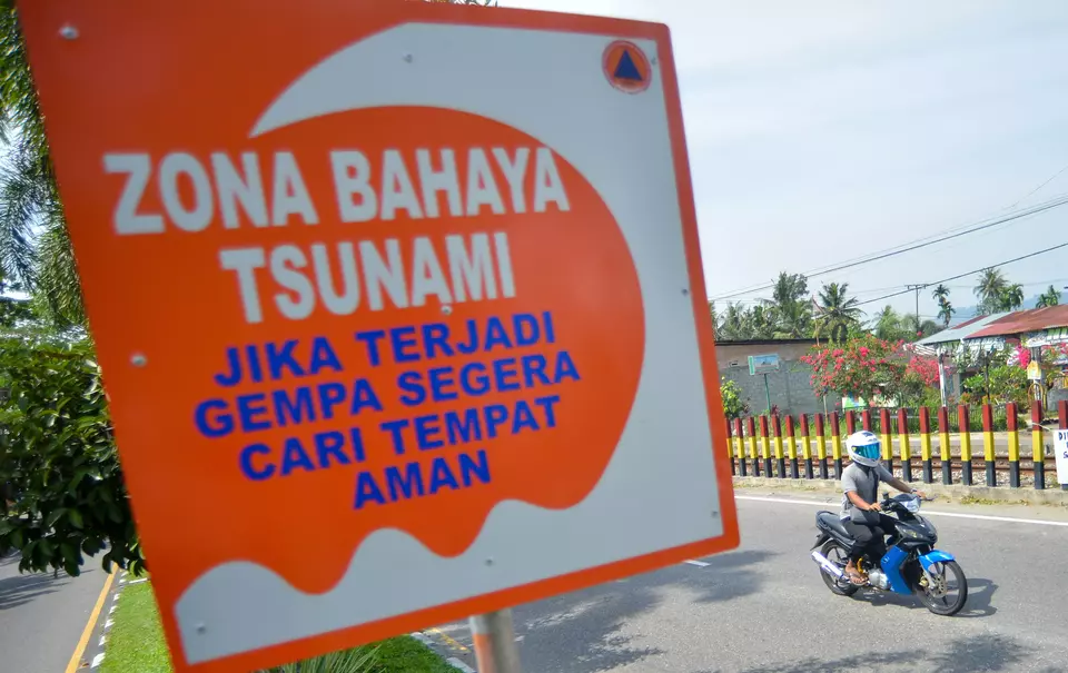 A motorcyclist passes by a sign board for a tsunami warning in West Sumatera on Feb. 11, 2025. (Antara Photo/Iggoy el Fitra)