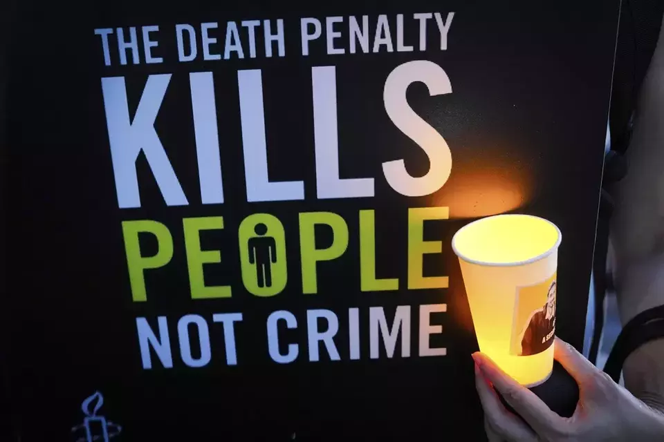 An activist holds a candle and a placard during a vigil against the impending execution of Malaysian national Pannir Selvam Pranthaman, sentenced to death for trafficking heroin into Singapore, outside the Singaporean embassy in Kuala Lumpur, Malaysia, Wednesday, Feb. 19, 2025. (AP Photo/Vincent Thian)