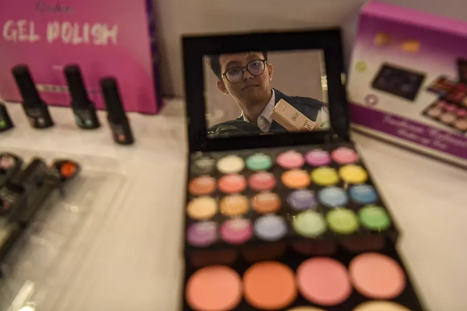 An officer inspects an illegal makeup palette during a press conference in Jakarta on Feb. 21, 2025. (Antara Photo/Muhammad Adimaja)