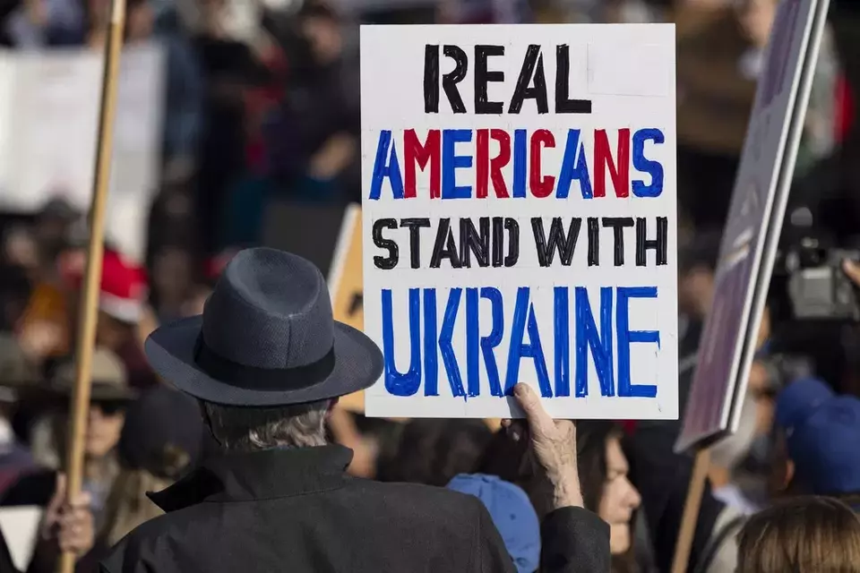 A demonstrator holds a poster reading, "Real Americans Stand with Ukraine," during a rally to protest President Donald Trump