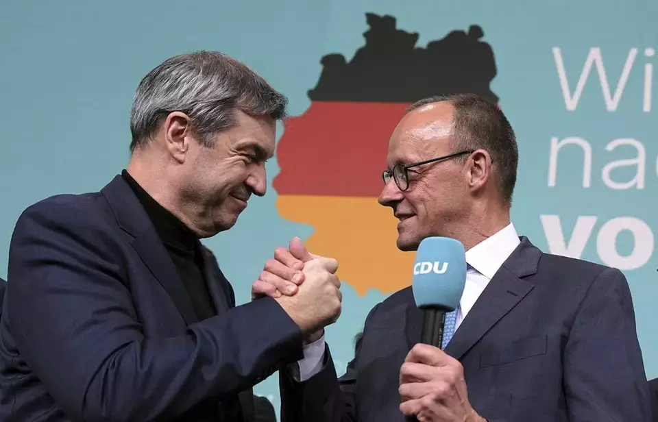 Friedrich Merz, right, leader of the Christian Democratic Union (CDU), and Markus Soeder, leader of the Christian Social Union (CSU), shake hands at the CDU party headquarters in Berlin, Germany, Sunday, Feb. 23, 2025. (Michael Kappeler/dpa via AP)
