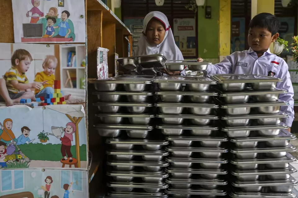 Children return the food trays used by the government-aided free meals at an elementary school in Banten on Feb. 18, 2025. (Antara Photo/Angga Budhiyanto)