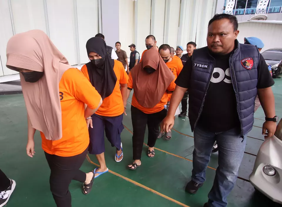 Police officers escort suspects accused of smuggling Indonesian workers who disguised as Umrah pilgrims at Soekarno-Hatta International Airport in Tangerang, Banten, Thursday, March 6, 2025. (Antara Photo/Muhammad Iqbal)