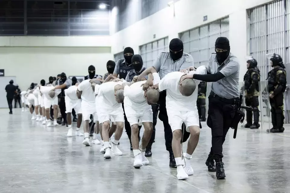 In this photo provided by El Salvador's presidential press office, prison guards transfer deportees from the US, alleged to be Venezuelan gang members, to the Terrorism Confinement Center in Tecoluca, El Salvador, Sunday, March 16, 2025. (El Salvador presidential press office via AP)