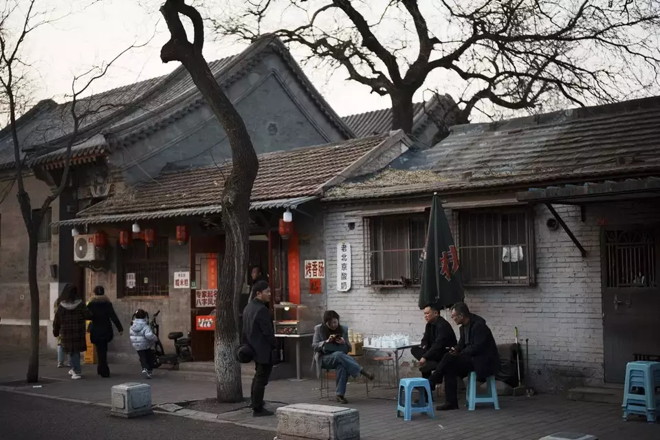 Residents sit outside their houses in the evening in downtown Beijing, China, Saturday, March 8, 2025. (AP Photo/Vincent Thian)
