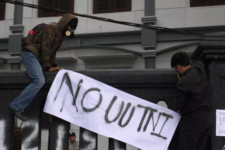 Protesters carry a poster opposing the passage of the military law during a rally in front of the Malang Legislative Council in Malang, East Java, Sunday, March 23, 2025. (Antara Photo/Ari Bowo Sucipto)