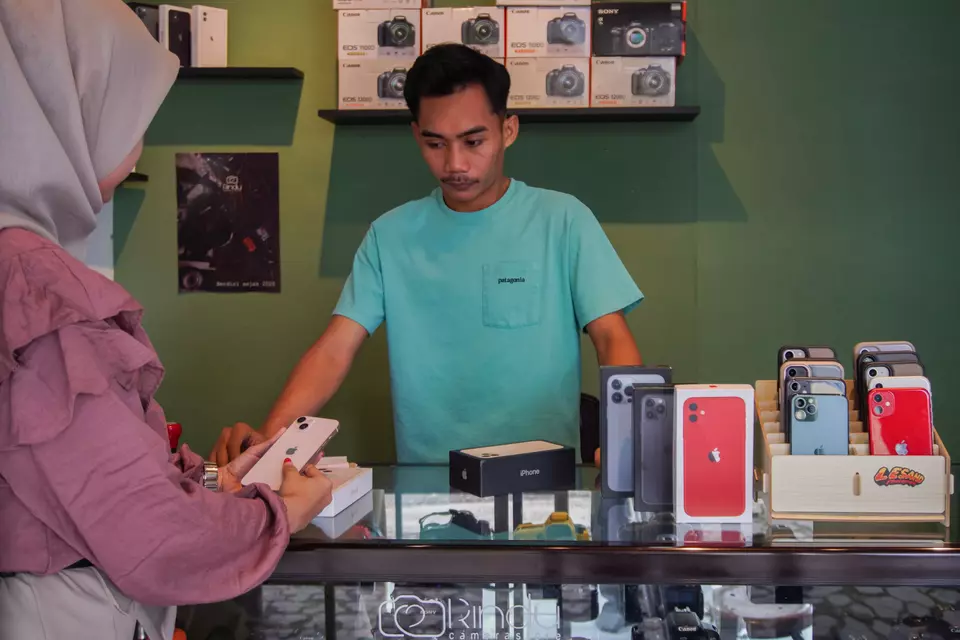 A shop owner leases iPhones to a customer in Kraksan District, Probolinggo Regency, East Java, Wedneday, March 26, 2025. (Antara Photo/Irfan Sumanjaya)