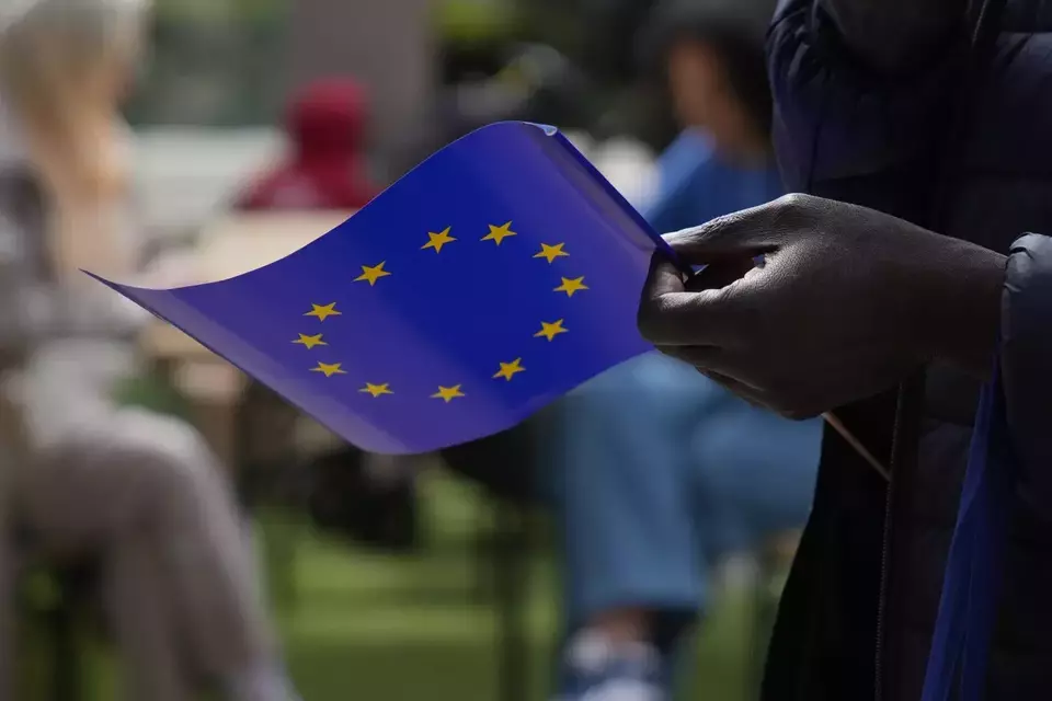 A man holds a European Union flag as he walks outside the European Commission building during Europe Day celebrations in Brussels on May 4, 2024. (AP Photo/Virginia Mayo File)