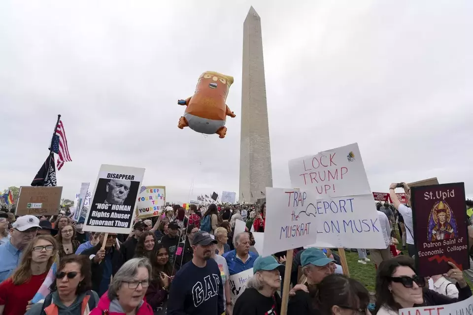 Demonstrators carry signs during the 'Hands Off!' protests against President Donald Trump and Elon Musk at the Washington Monument in Washington, Saturday, April 5, 2025. (AP Photo/Jose Luis Magana)