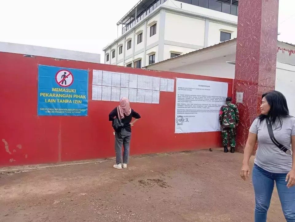A worker reads a layoff notice on the Yihong Novatex footwear factory gate in Astanajapura District, Cirebon, West Java, Sunday, April 6, 2025. (B-Universe Photo/Dede Adhitama)