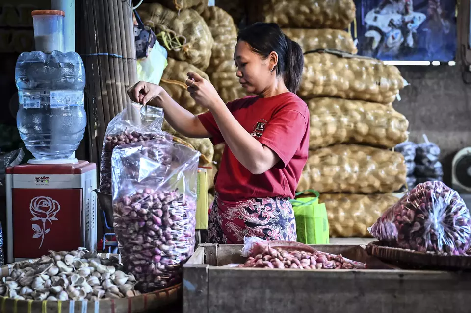 A woman weighs a sack of shallots at a traditional market in Semarang, Central Java, on March 18, 2025. (Antara Photo/Aprillio Akbar)