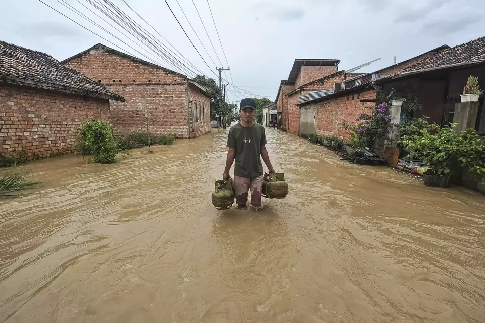 A man passes through a flooded residential area in Kenali Besar, Jambi, on March 30, 2025. (Antara Photo/Wahdi Septiawan)