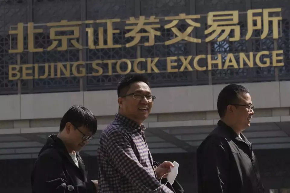 People walk by the Beijing Stock Exchange on Financial Street in Beijing, Thursday, April 10, 2025. (AP Photo/Andy Wong)