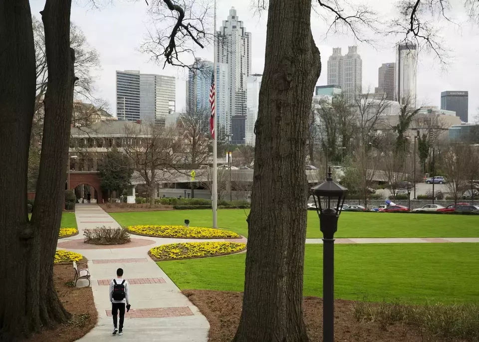 FILE - A person walks through the Georgia Tech campus with the downtown skyline in the background, March 11, 2016, in Atlanta. (AP Photo/David Goldman, File)