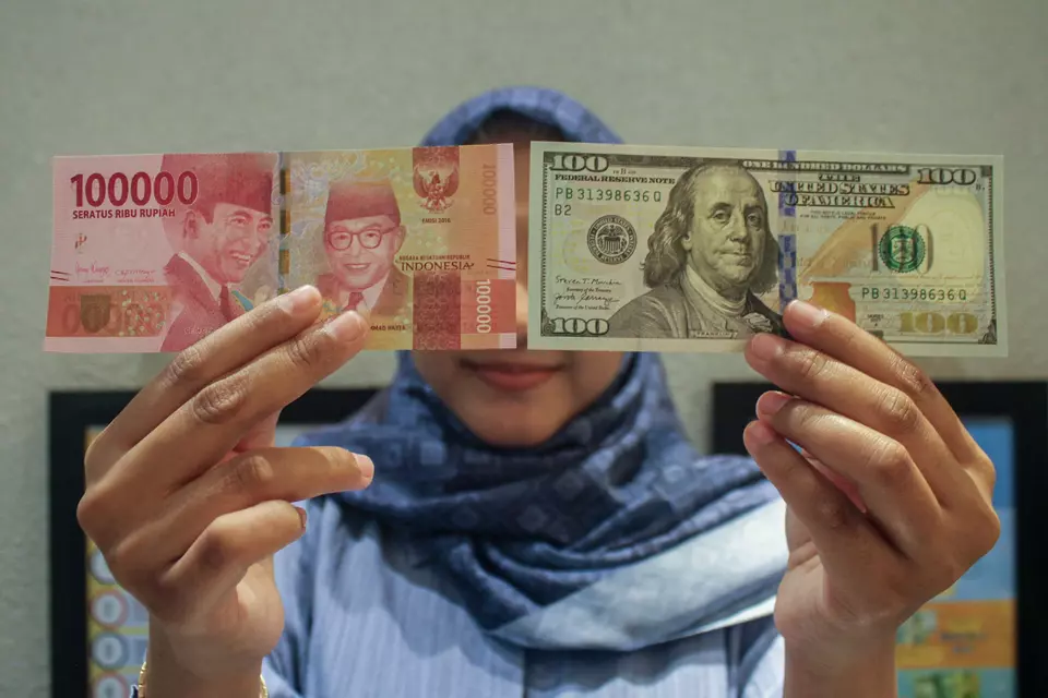 A woman shows American dollar and Indonesian rupiah banknotes at a money changer in Jakarta on April 8, 2025. (Antara Photo/Fathul Habib Sholeh)