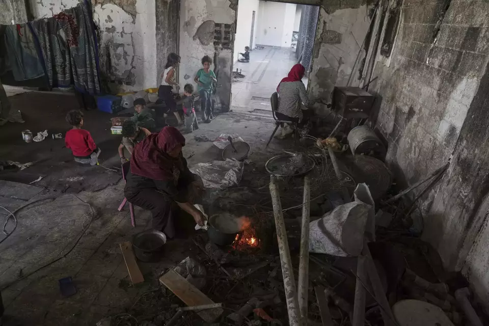 Hiam Al-Kafarna prepares food on a fire for her family at the Islamic University in Gaza City, now a shelter for displaced Palestinians amid the ongoing war in Gaza, on April 4, 2025. (AP Photo/Jehad Alshrafi)