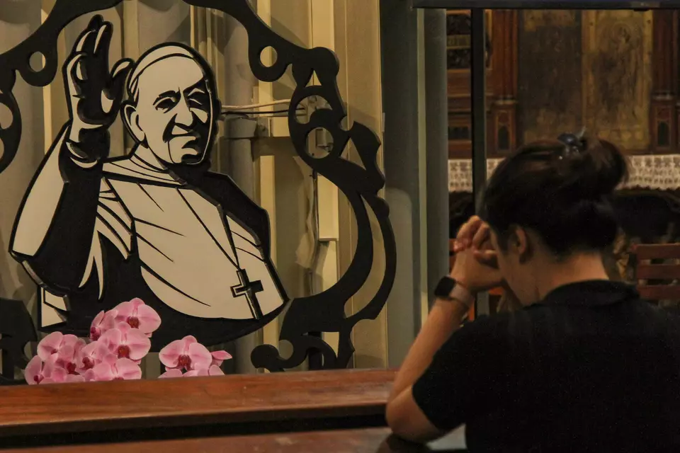 A woman prays in front of a wood crafting depicting Pope Francis at the Jakarta Cathedral, Monday, April 21, 2025. (Antara Photo/Fathul Habib Sholeh)
