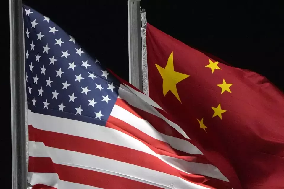 FILE - The American and Chinese flags wave at Genting Snow Park ahead of the 2022 Winter Olympics, Feb. 2, 2022, in Zhangjiakou, China. (AP Photo/Kiichiro Sato, File)